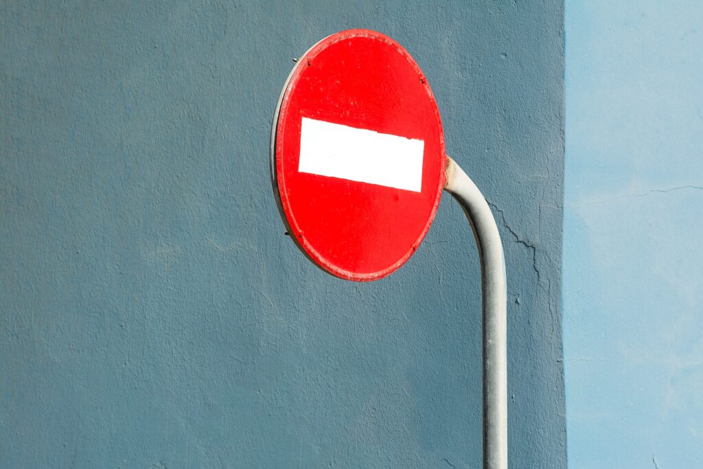 A close up of a "do not enter" sign on a blue concrete wall indicating danger.