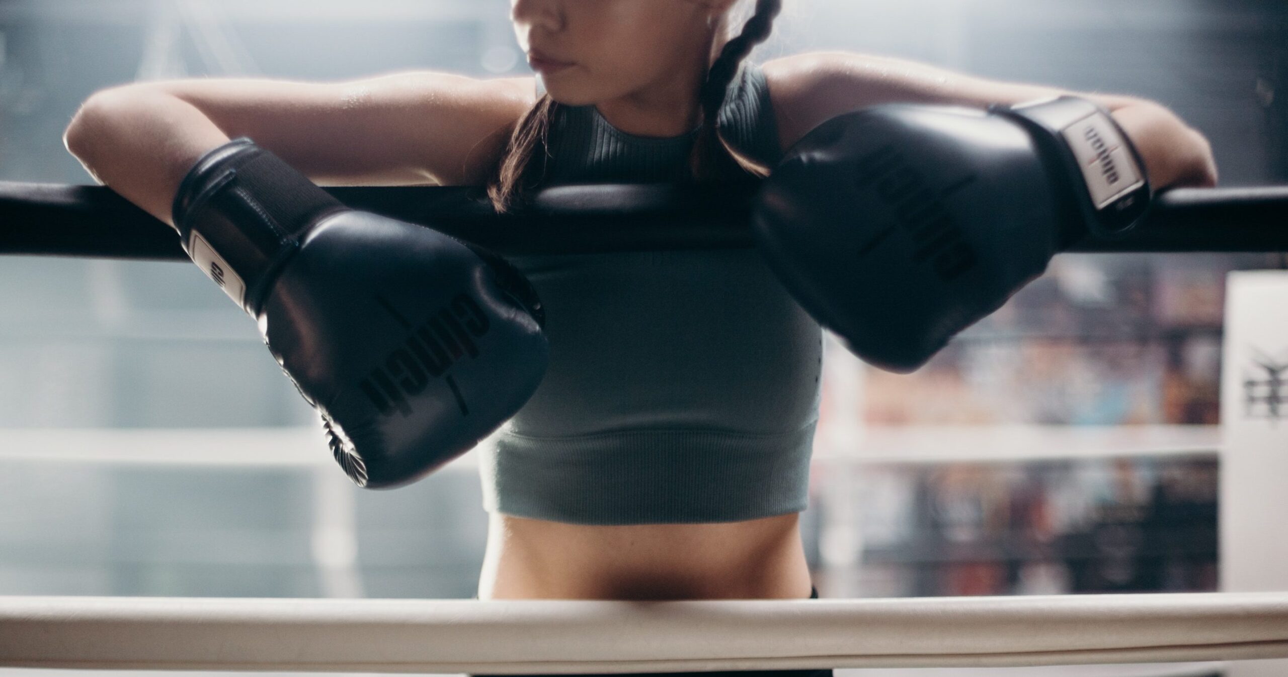 woman leaning on ropes in boxing ring