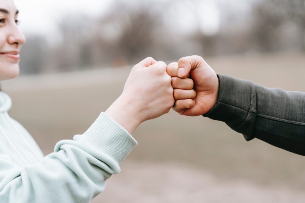 A woman bumping fists with an unseen (probably) man 