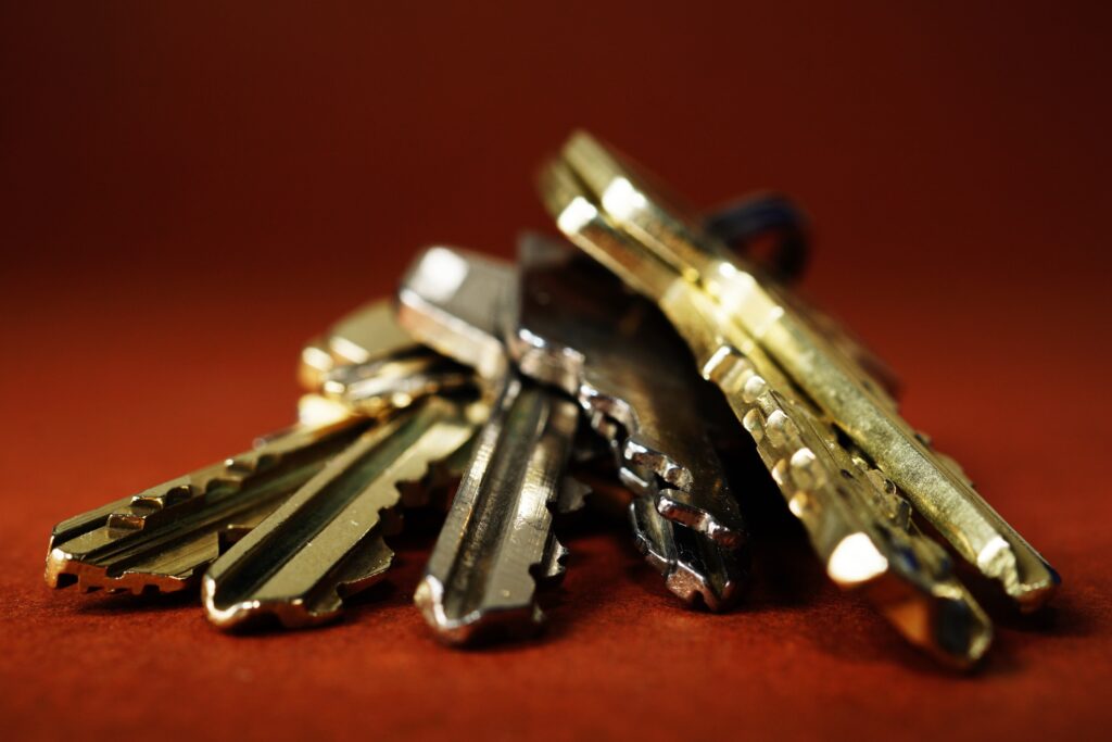 A close-up of shiny metal keys against a burnt-red background. 