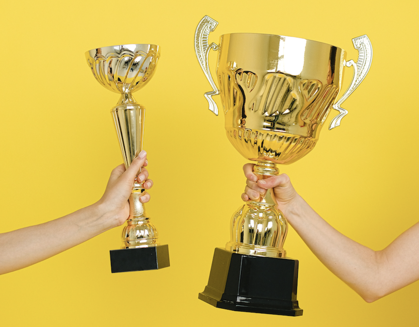 Two arms extending golden trophies towards each other against a golden background